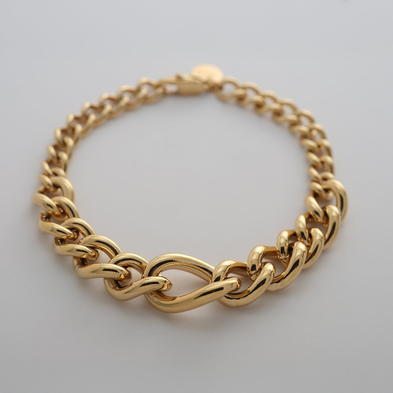 Bracciale Guido Maria Kretschmer, acciaio inossidabile placcato oro giallo, look catena, maglia ovale, sfondo bianco.