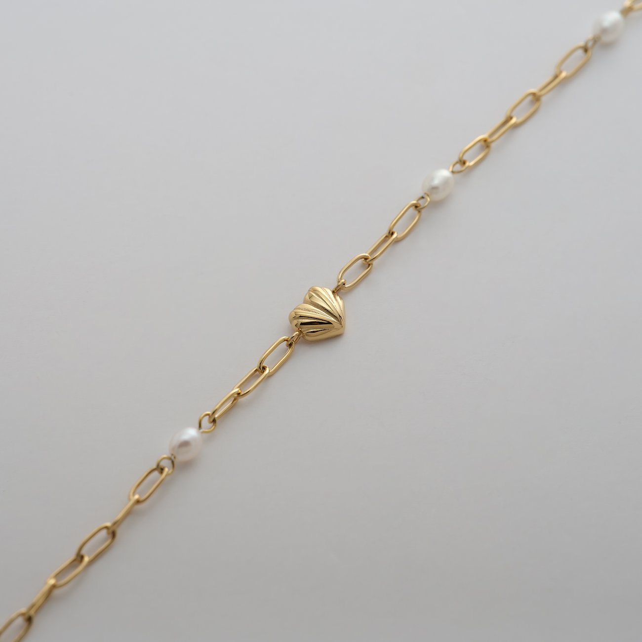 Guido Maria Kretschmer armband i guldfärgat rostfritt stål med hjärtdetalj och vita pärlor.