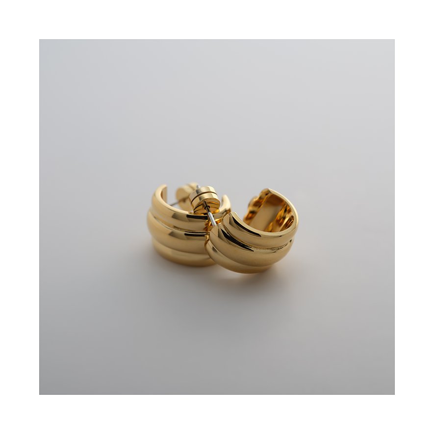 Ein glänzendes, gerilltes Guido Maria Kretschmer Creolen-Paar aus goldenem Edelstahl auf hellem Hintergrund.