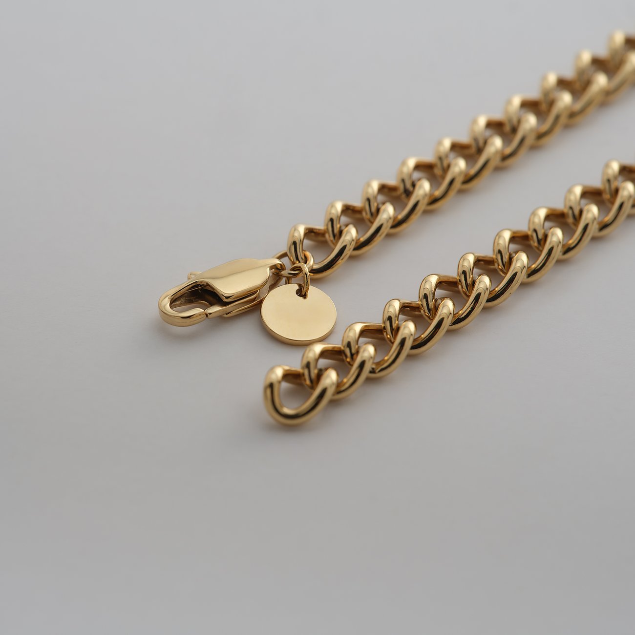 Nahaufnahme einer dicken, goldenen Kette von Guido Maria Kretschmer aus Edelstahl mit Karabinerverschluss.