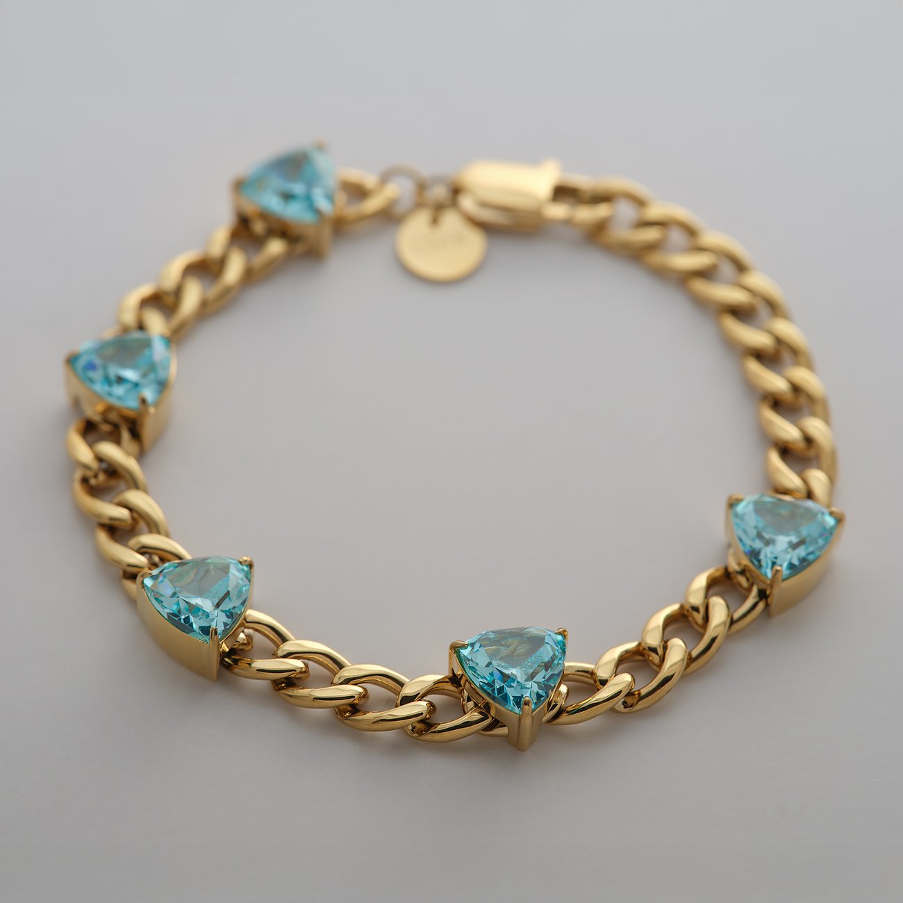 Guido Maria Kretschmer Armschmuck aus goldfarbenem Edelstahl mit hellblauen, herzförmigen Zirkonia Farbedelsteinen.