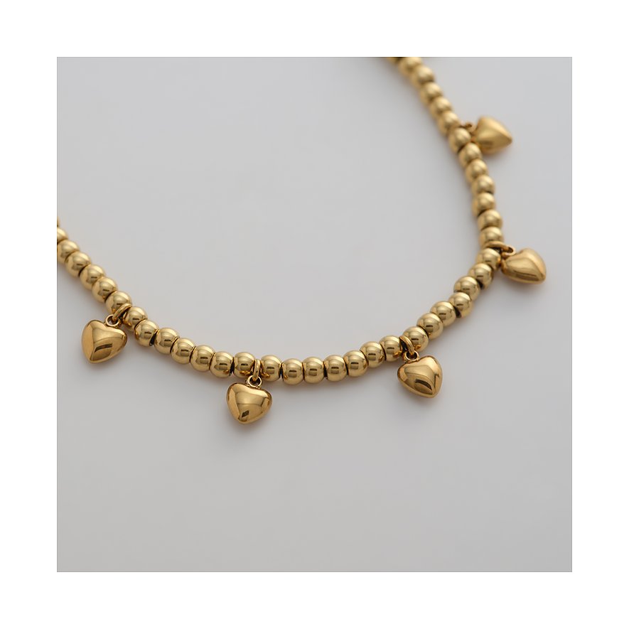 Primo piano di un bracciale dorato Guido Maria Kretschmer in acciaio inox con piccole perle e ciondoli a cuore.