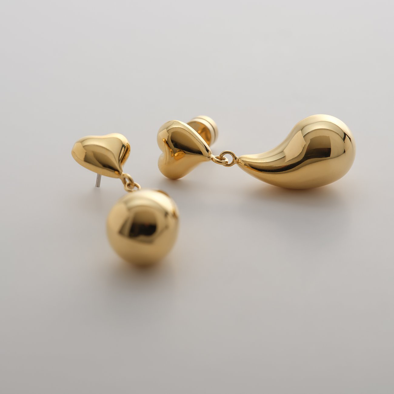 Boucles d'oreilles Guido Maria Kretschmer en acier inoxydable jaune brillant, en forme de cœur et de goutte.