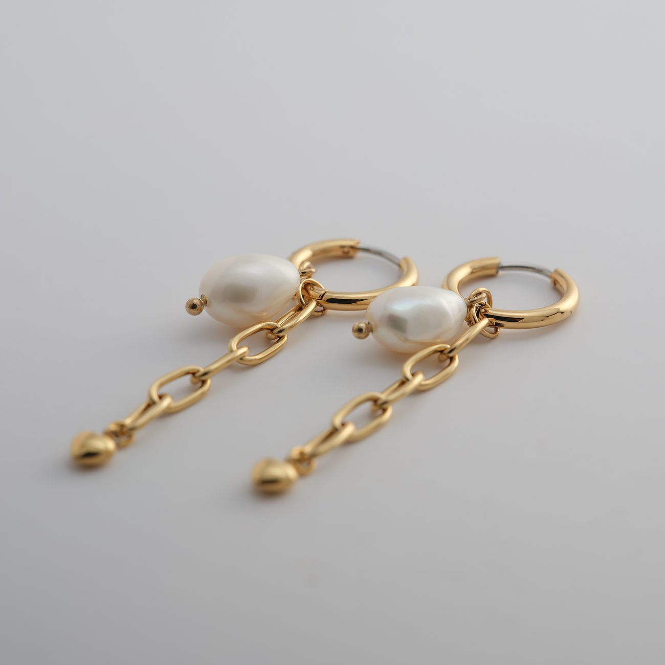 Guido Maria Kretschmer Ohrschmuck aus gelbvergoldetem Edelstahl mit Perlen, die an feinen Ketten hängen.