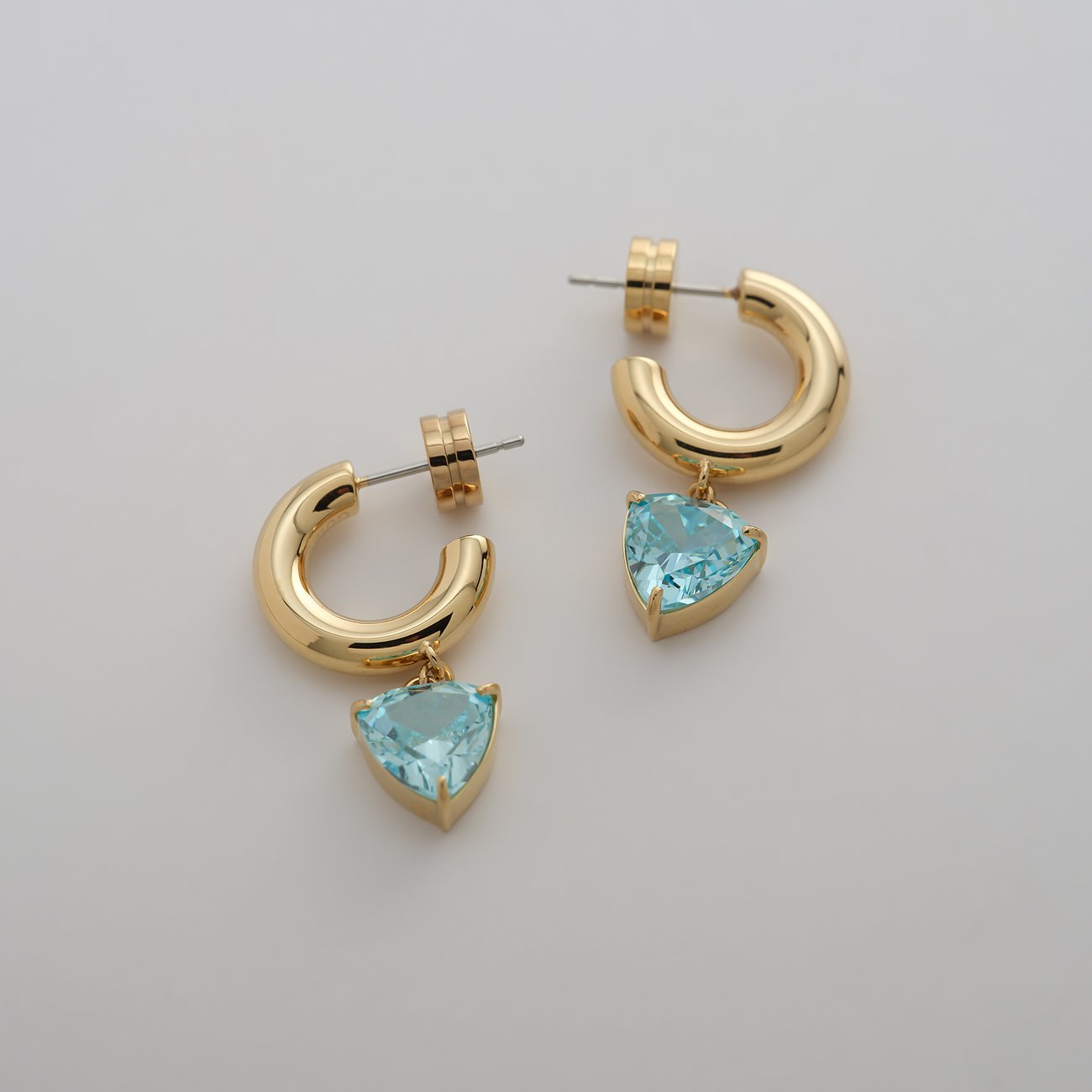 Guido Maria Kretschmer Ohrschmuck aus goldfarbenem Edelstahl mit hellblauen Zirkonia Farbedelsteinen.