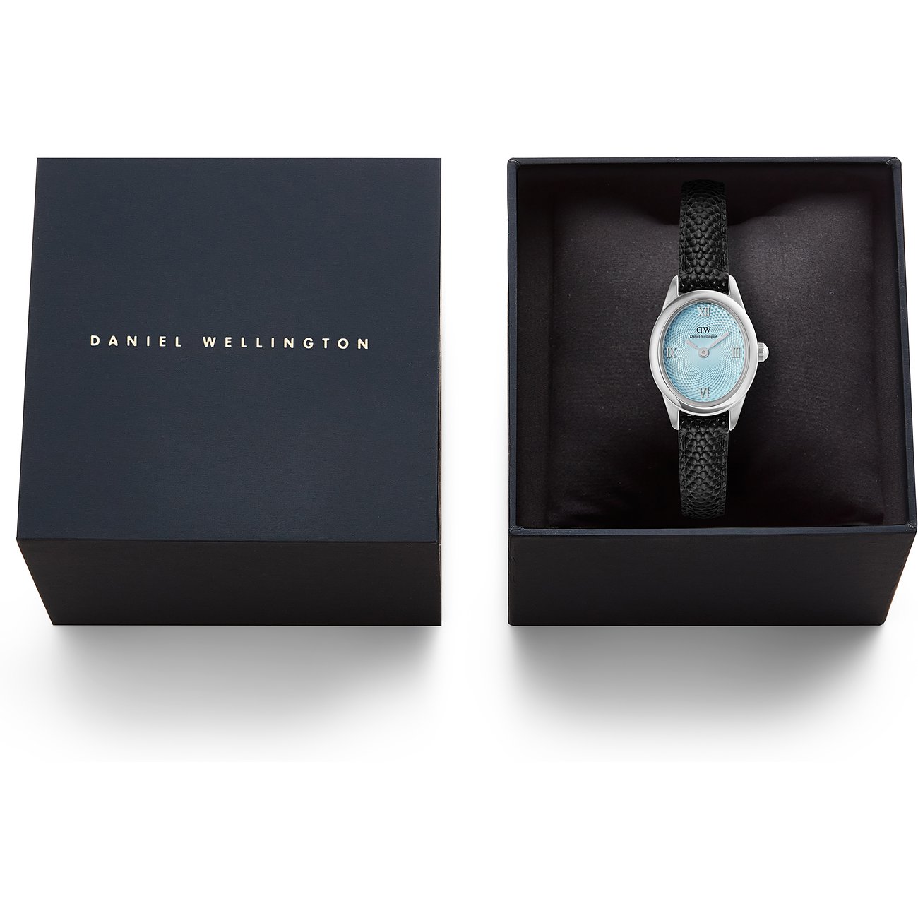 Daniel Wellington Damenuhr mit Lederarmband in offener Box neben dem Deckel. Helles Zifferblatt.