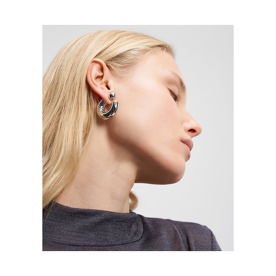 Nahaufnahme einer Frau, die Liebeskind Edelstahl-Creolen trägt. Die Ohrringe sind glänzend und wirken massiv.