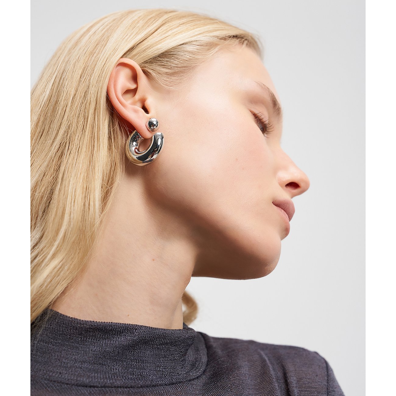 Nahaufnahme einer Frau, die Liebeskind Edelstahl-Creolen trägt. Die Ohrringe sind glänzend und wirken massiv.