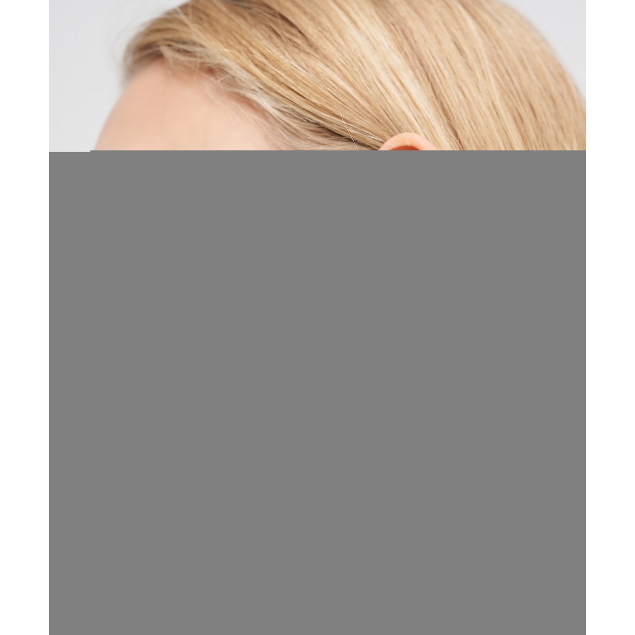 Close-up van een vrouw met blond haar die een oorbel draagt.