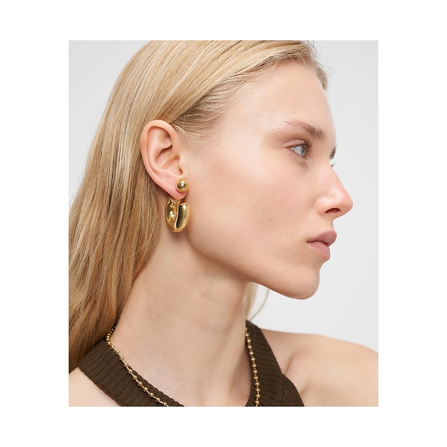 Close-up van de gouden Liebeskind oorbel van roestvrij staal, gedragen aan één oor.