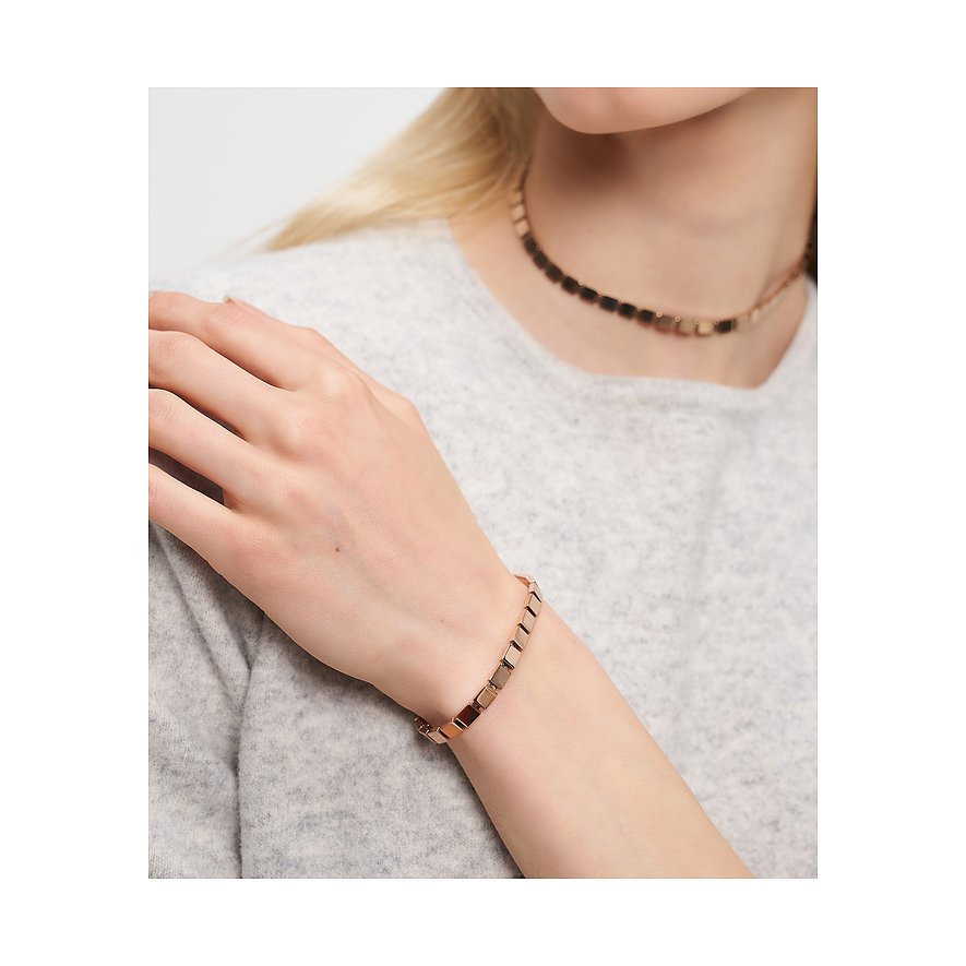 Roséguld Liebeskind-armband med kubformade länkar på kvinnas handled. Matchande halsband i bakgrunden.
