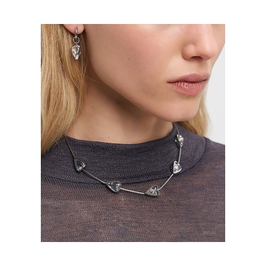 Primo piano di una donna con una collana Liebeskind in acciaio inossidabile e gemme chiare a forma di cuore.