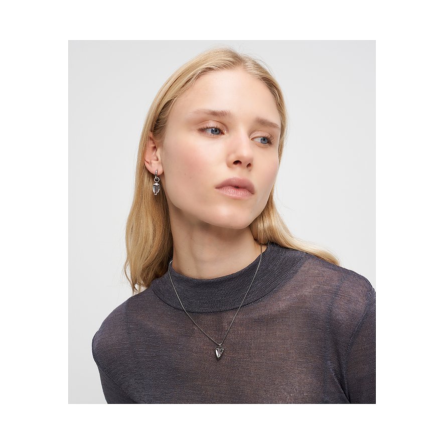 En model bærer Liebeskind øreringe og en matchende halskæde i rustfrit stål med en klar sten.