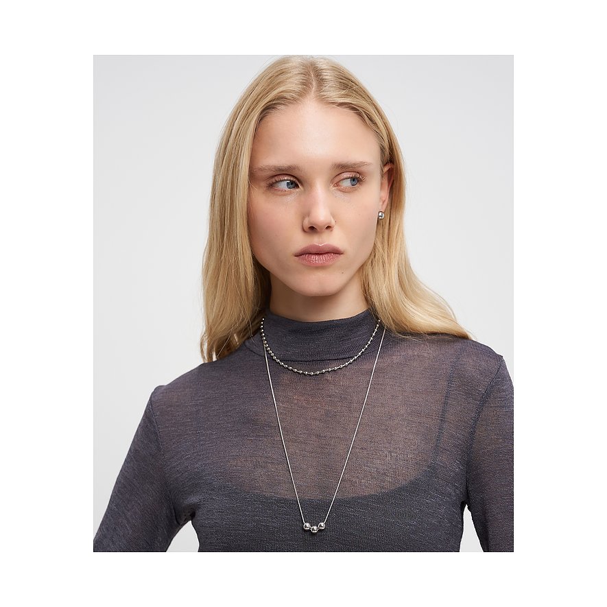 Model trägt zwei Liebeskind Edelstahlketten: eine kurze Kugelkette und eine lange Kette mit drei Kugeln auf der Brust.
