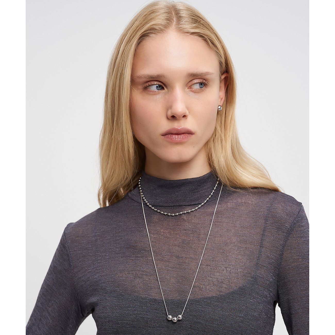 Model trägt zwei Liebeskind Edelstahlketten: eine kurze Kugelkette und eine lange Kette mit drei Kugeln auf der Brust.