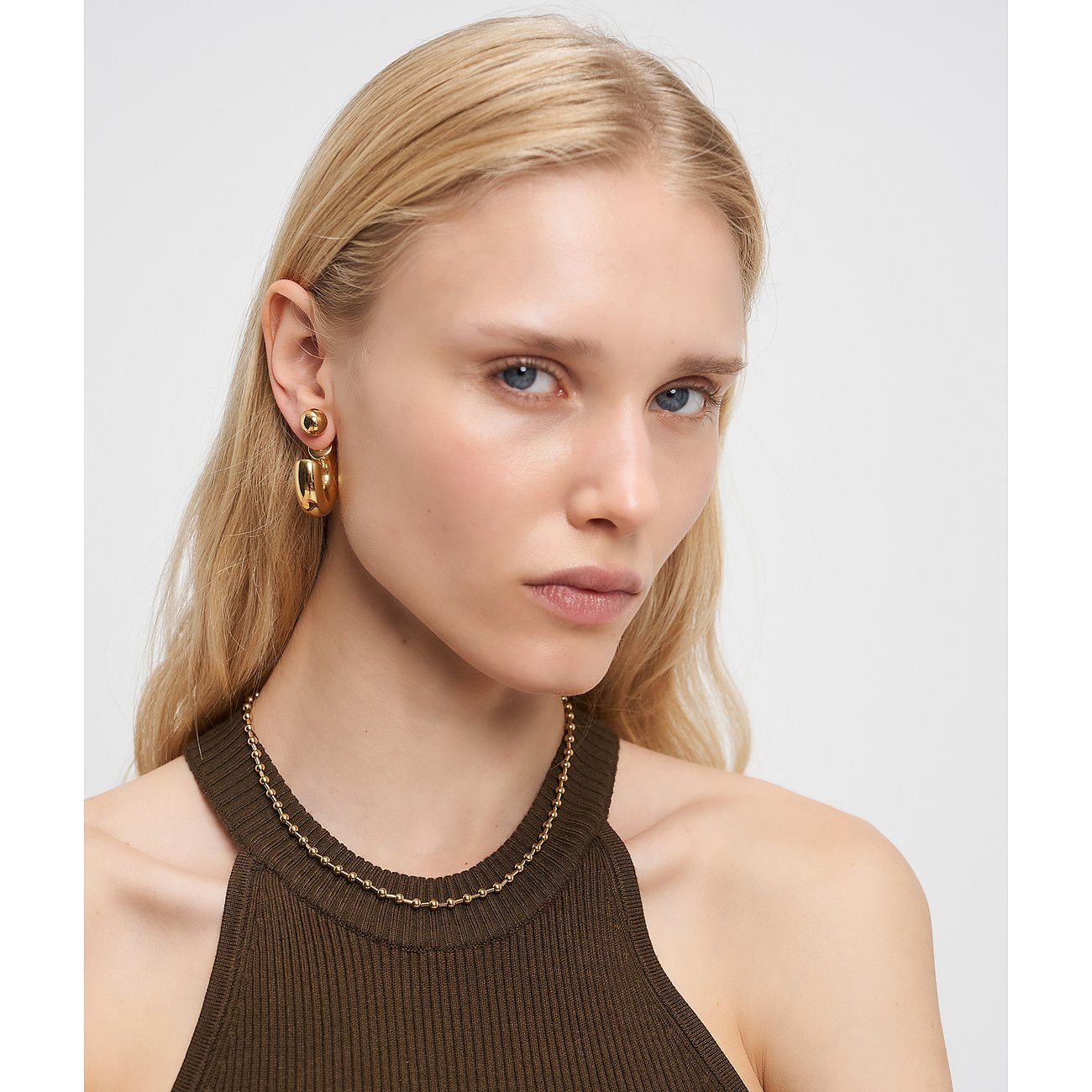Model trägt eine goldfarbene Liebeskind Halskette aus Edelstahl, die eng am Hals anliegt.