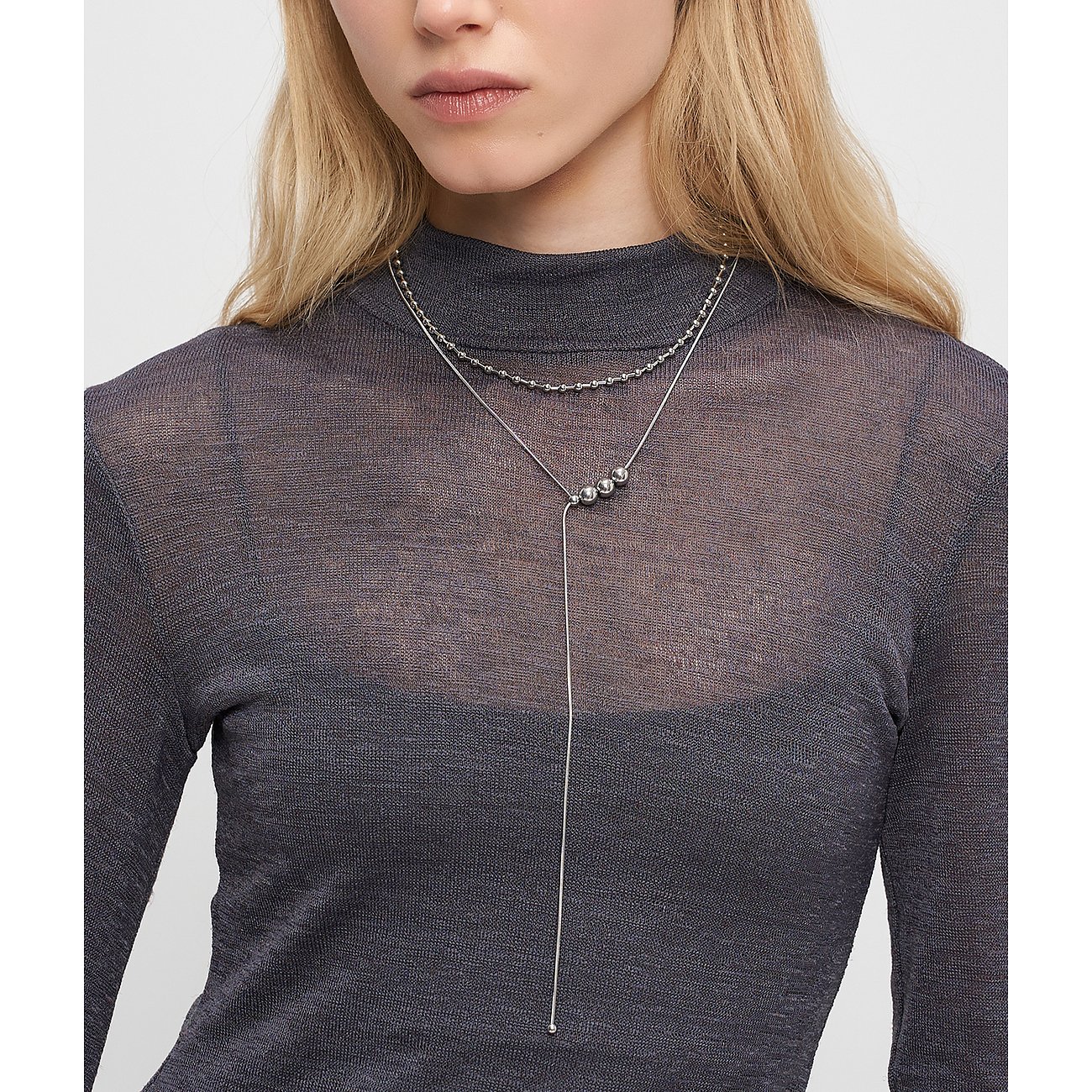 Femme portant le collier Liebeskind en acier inoxydable brillant, un bijou multicouche avec des sphères pendantes.