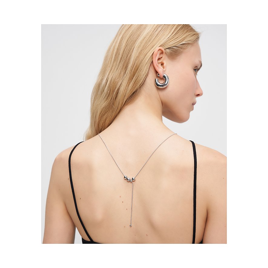 Vue arrière d'une femme aux longs cheveux blonds, portant un collier Liebeskind ouvert en acier avec trois perles.