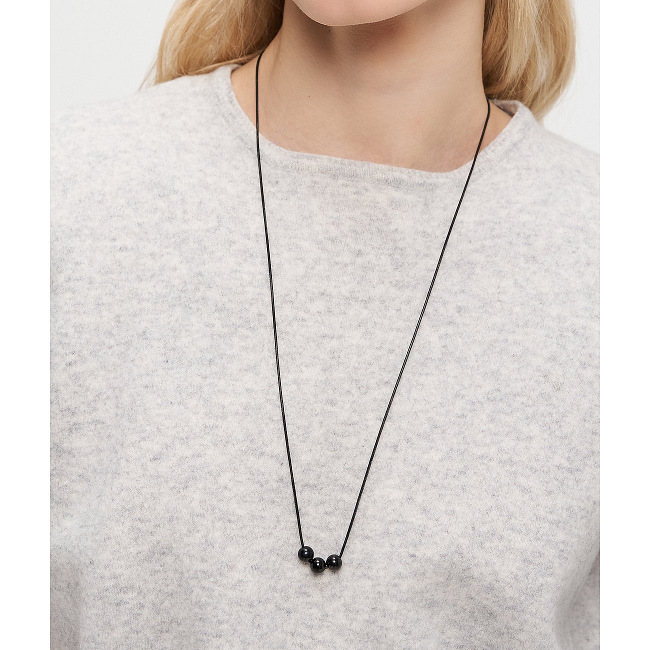 Närbild av kvinna med Liebeskind halsband: svart tråd med tre kulor i rostfritt stål.