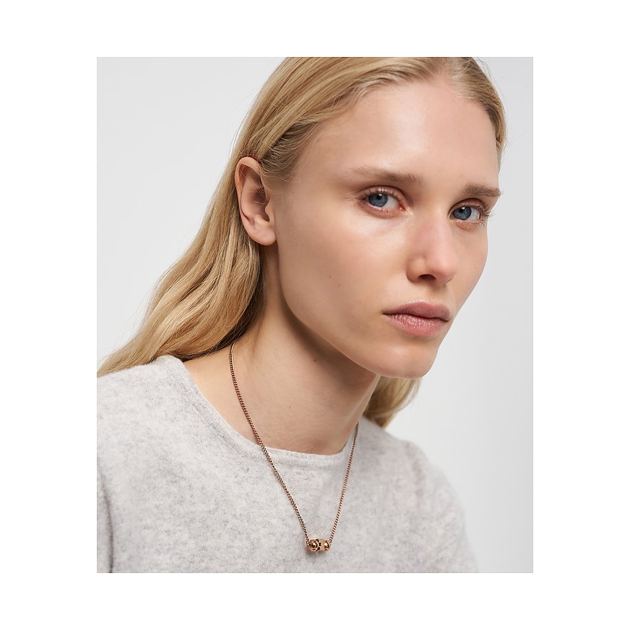 Närbild av kvinna som bär ett roséguldfärgat Liebeskind-halsband i rostfritt stål med två små runda berlocker.