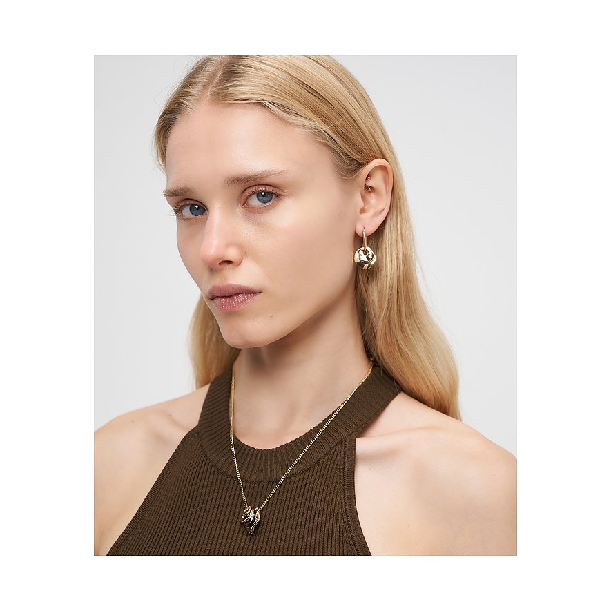 Eine blonde Frau tr g einen eleganten Halsschmuck und Ohrringe der Marke Liebeskind aus goldfarbenem Edelstahl.