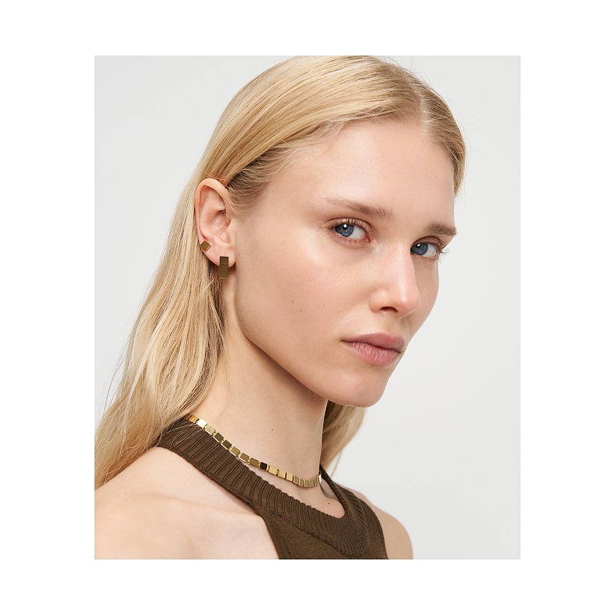 Nahaufnahme einer Frau, die goldfarbenen Liebeskind Edelstahlohrschmuck in geometrischen Formen trägt.