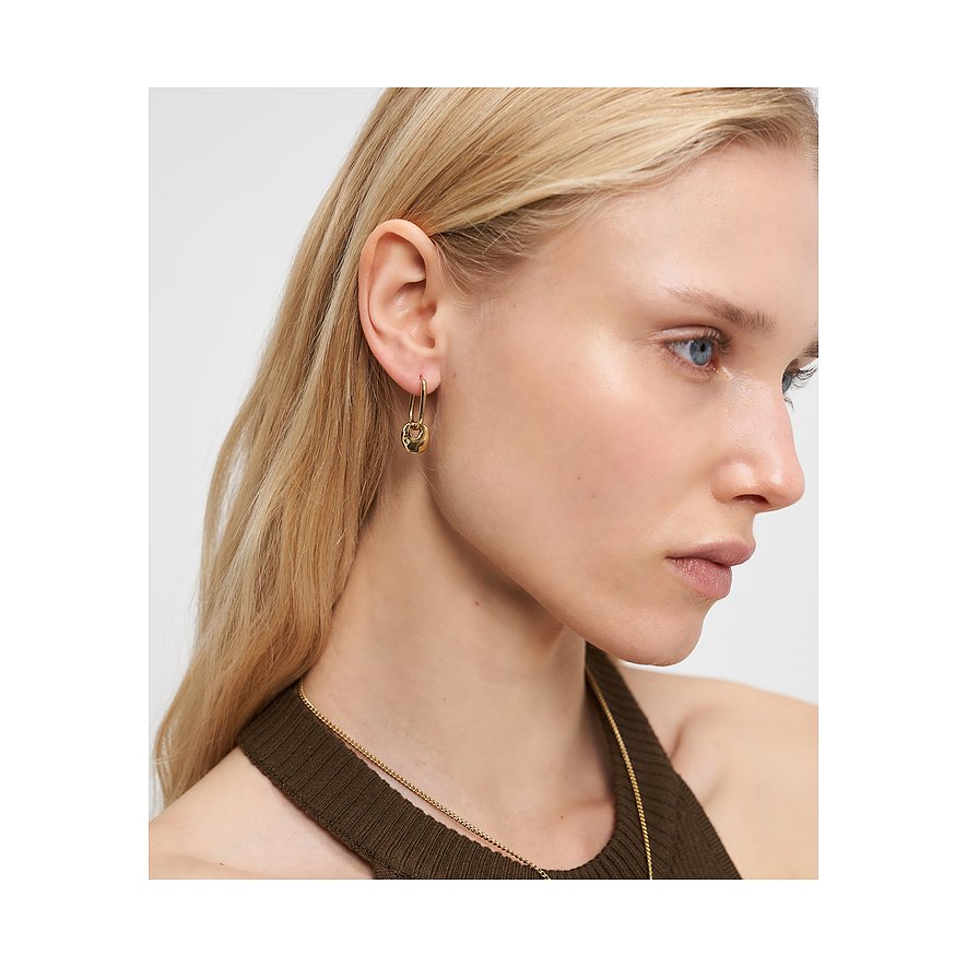 Een vrouw draagt een gouden Liebeskind roestvrijstalen oorbel met een hangende, gestructureerde hanger aan haar rechteroor.