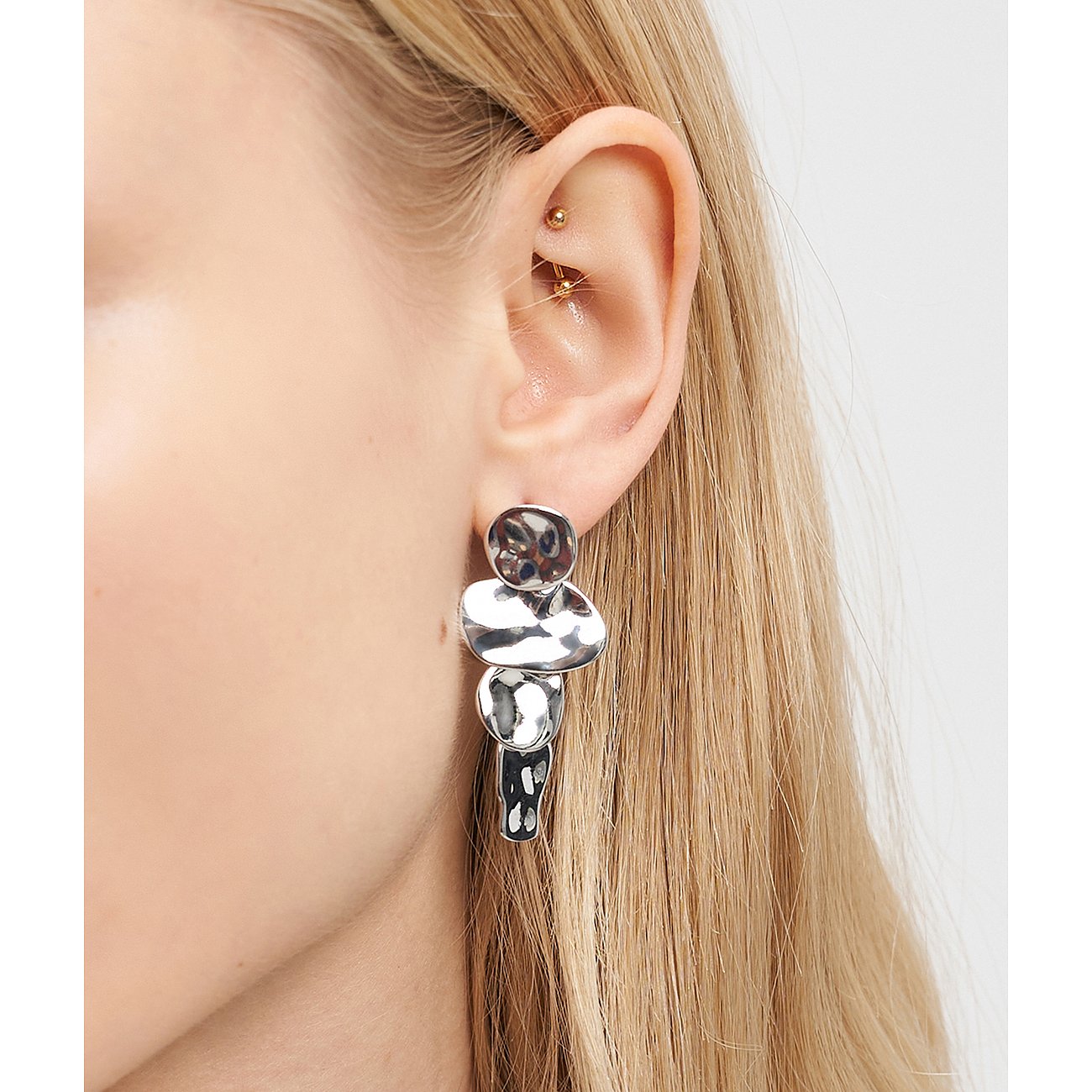 Liebeskind Ohrschmuck aus glänzendem Edelstahl am Ohr einer Person, bestehend aus vier unregelmäßig geformten Gliedern.