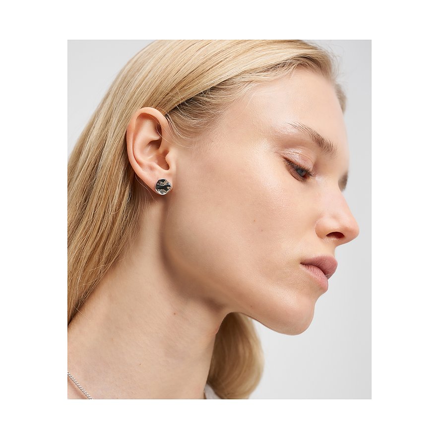 Una donna indossa un orecchino a lobo rotondo Liebeskind in acciaio inox con una gemma chiara tagliata sull'orecchio destro.