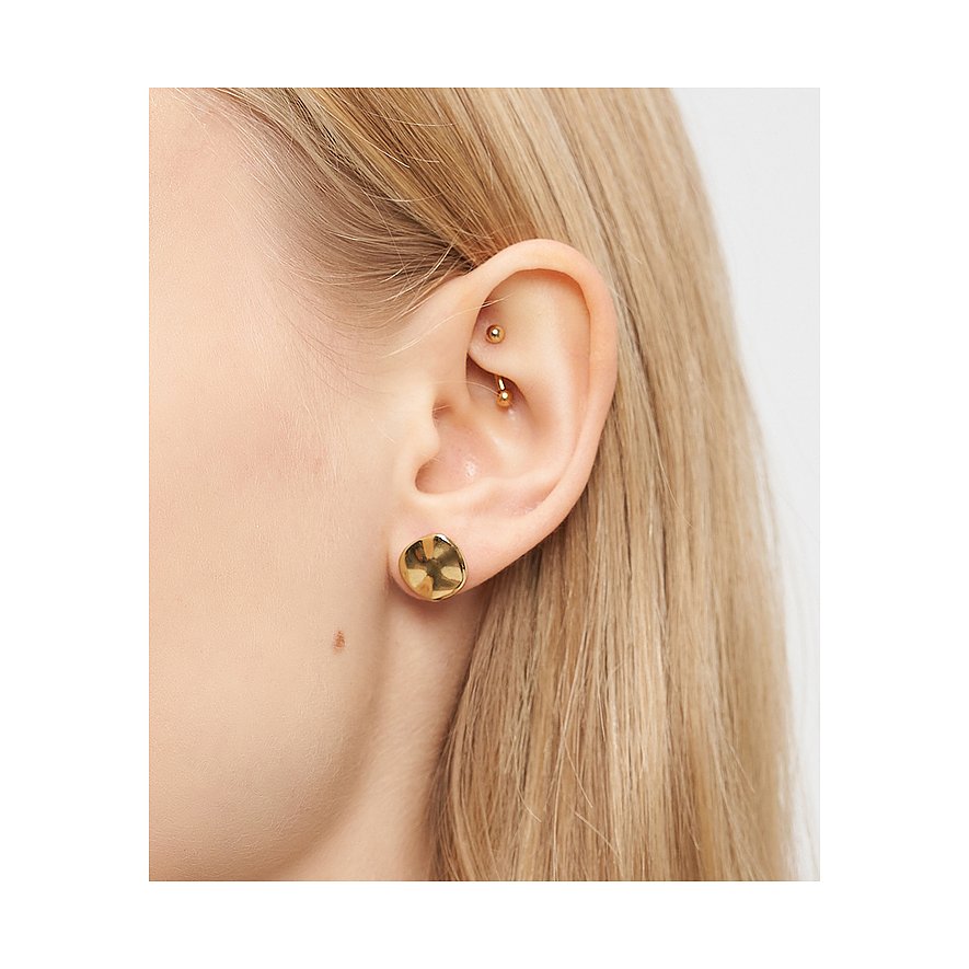 Primo piano di un orecchio con orecchino Liebeskind in acciaio inossidabile placcato oro, forma a disco martellato.