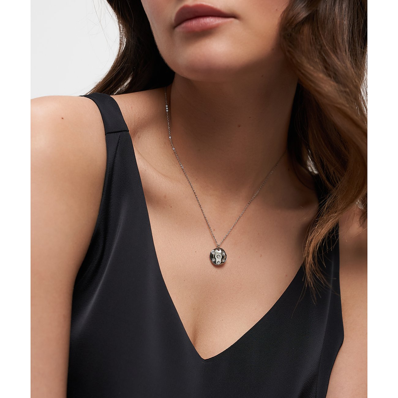 Frau trägt kurze Tamaris Edelstahlkette mit rundem Anhänger, der in der Mitte mit einem Zirkonia besetzt ist.