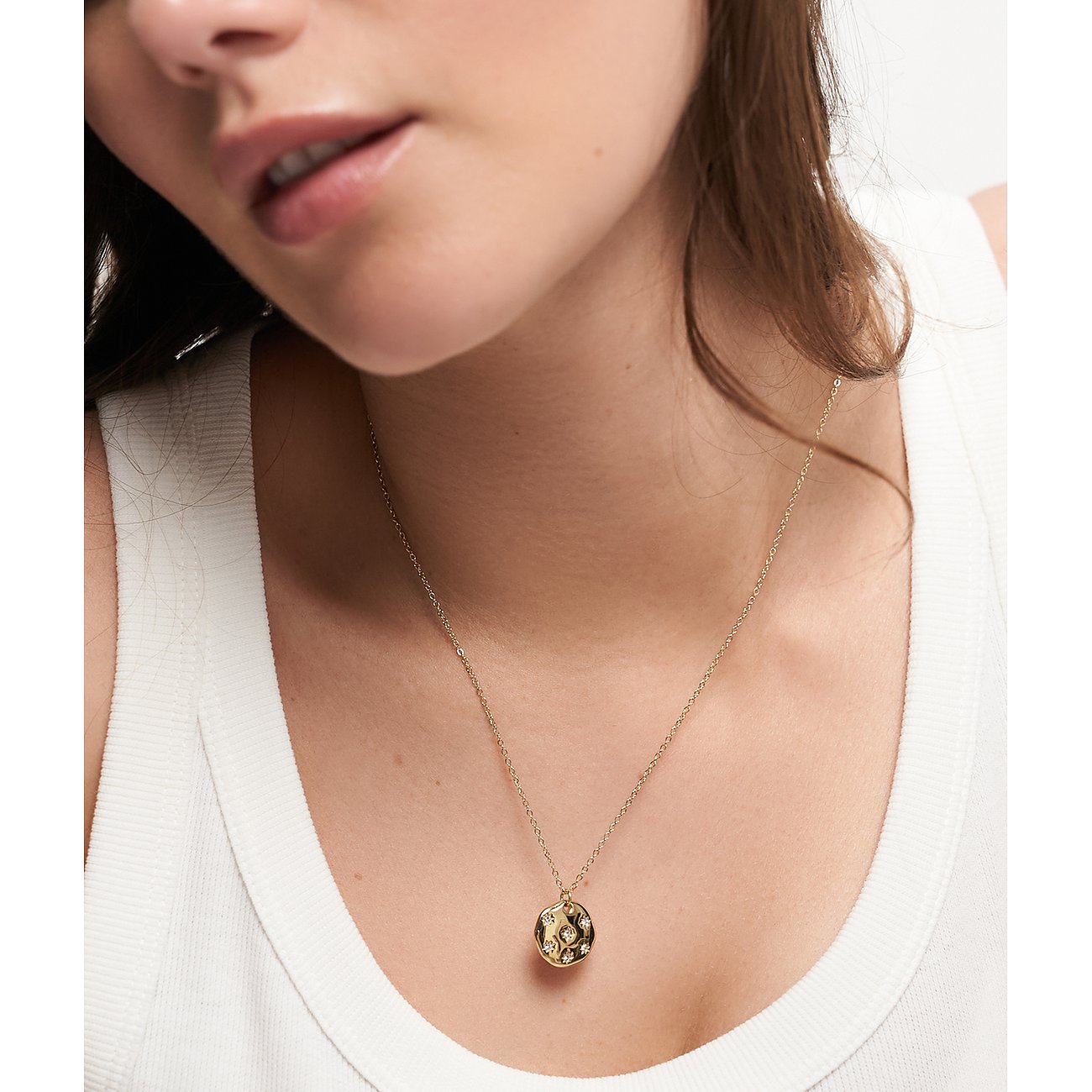 Close-up van een vrouw met een Tamaris ketting van goudkleurig roestvrij staal met zirkonia-gezette hanger.