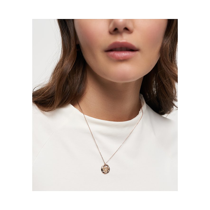 Primo piano di una donna con collana Tamaris in acciaio inossidabile placcato oro rosa con pendente rotondo in zircone.