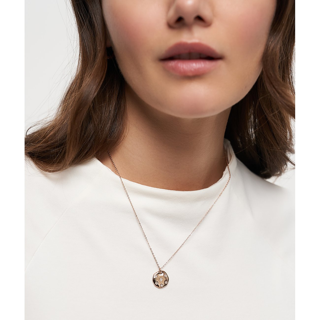 Primo piano di una donna con collana Tamaris in acciaio inossidabile placcato oro rosa con pendente rotondo in zircone.