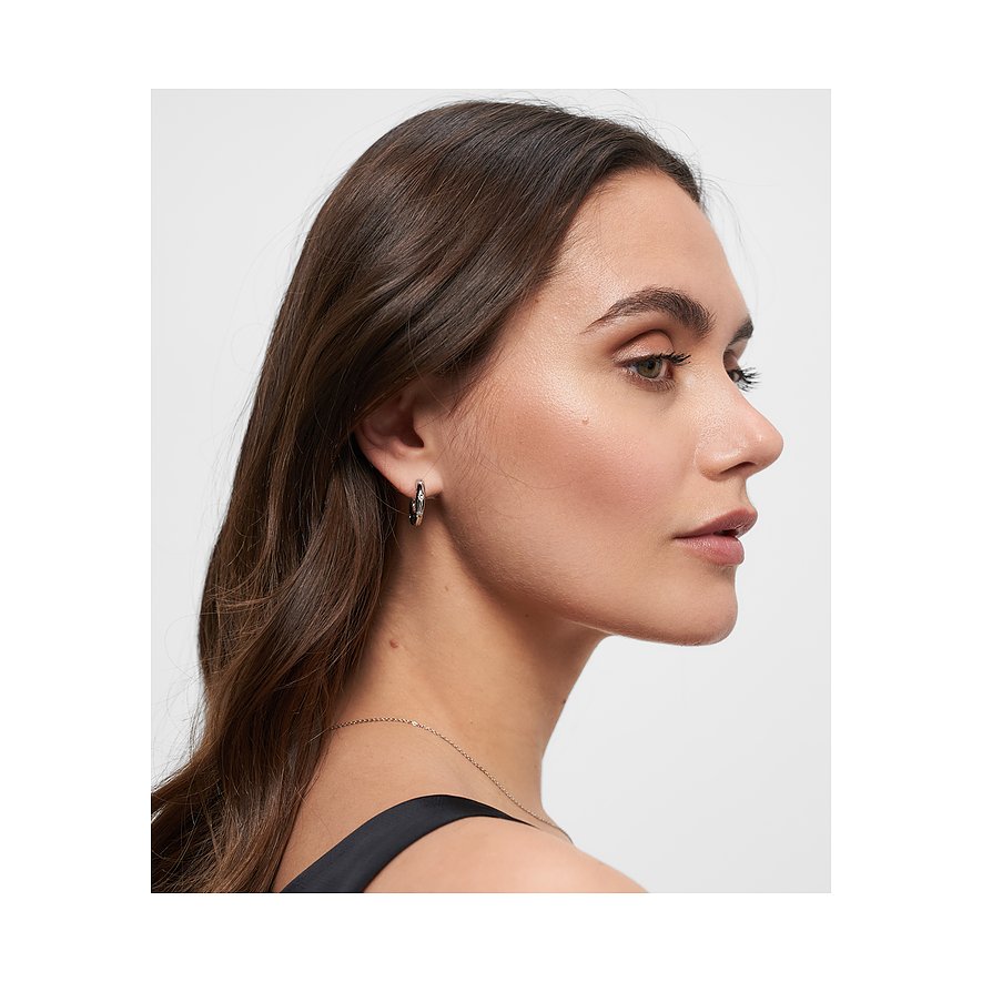 En kvinna bär ett Tamaris örhänge i rostfritt stål med glittrande glasstenar, synligt från sidan.