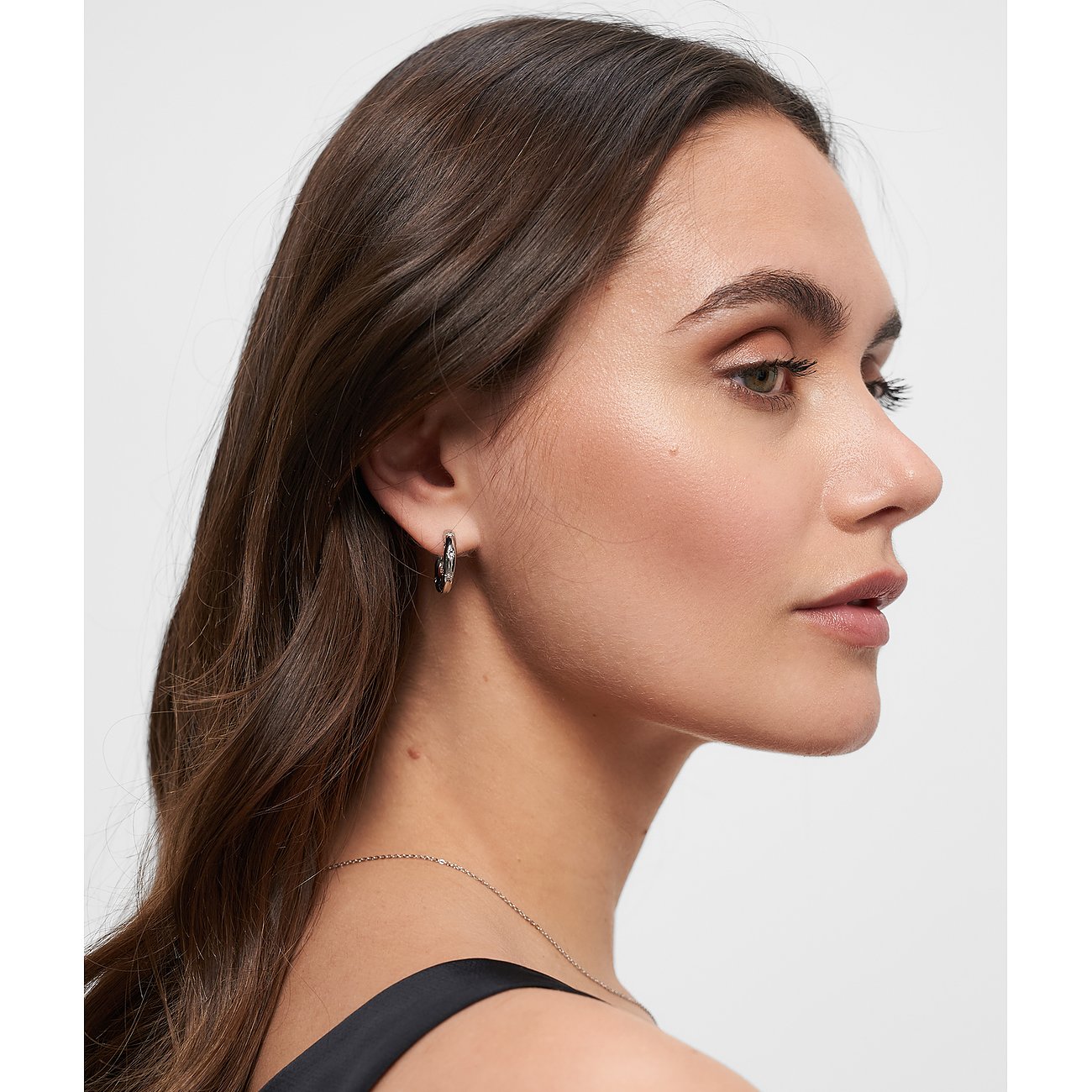 En kvinna bär ett Tamaris örhänge i rostfritt stål med glittrande glasstenar, synligt från sidan.