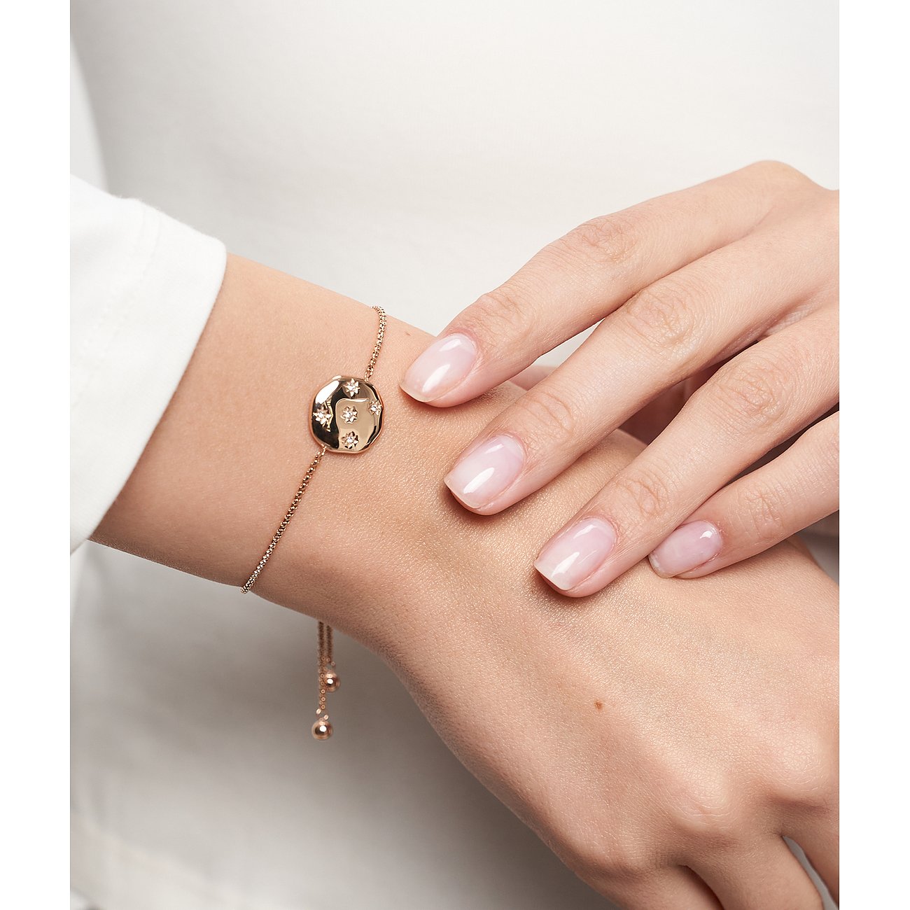 Dieses rosévergoldete Tamaris Edelstahl-Armband mit Zirkonia-besetztem Anhänger ziert ein Handgelenk.