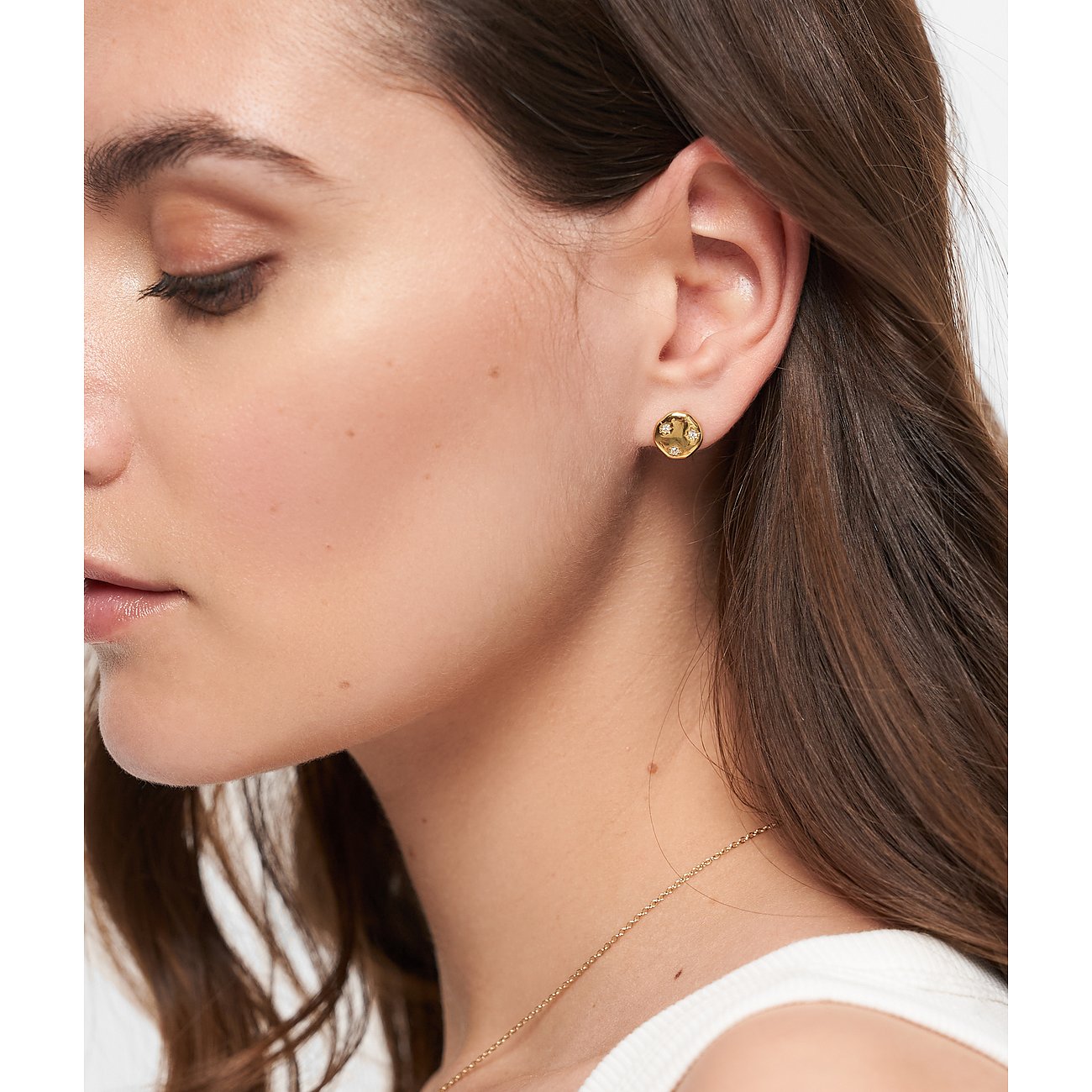 Nahaufnahme einer Frau mit einem runden Tamaris Ohrstecker aus goldenem Edelstahl mit Zirkonia im Ohr.