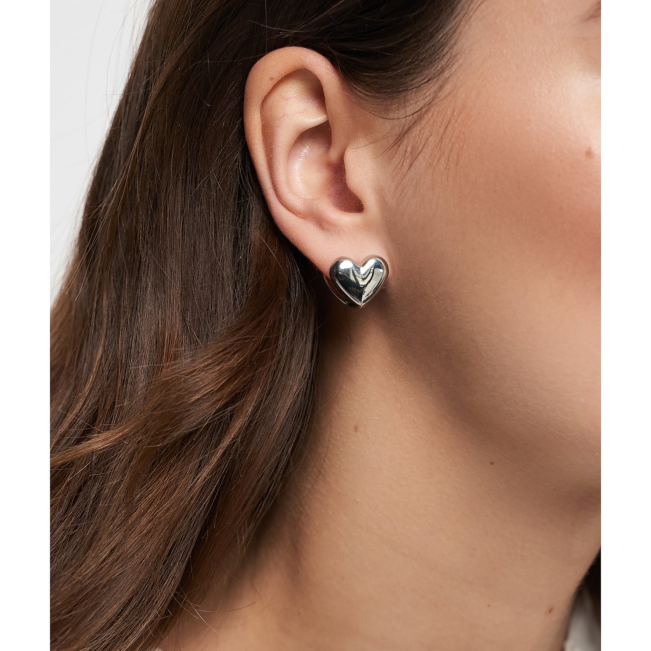 Nahaufnahme eines Tamaris Edelstahl-Ohrsteckers in Herzform am Ohr einer Person.