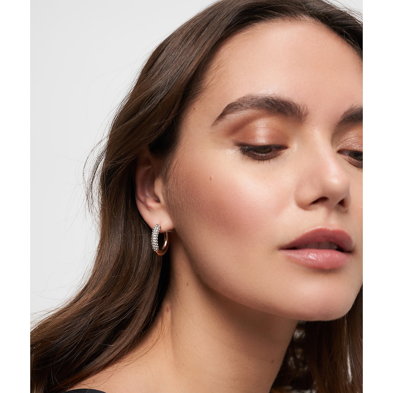 Närbild på kvinna som bär ett Tamaris öronsmycke i rostfritt stål med glasstenar.