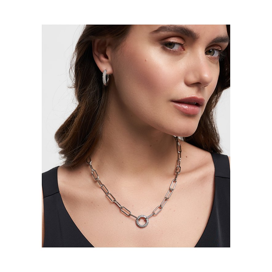 Eine Frau trägt eine Tamaris Edelstahlkette mit groben Gliedern und einem runden Anhänger mit Glassteinen.