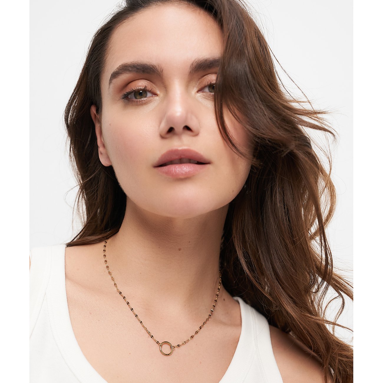 Nahaufnahme eines Modells, das eine feingliedrige, goldene Tamaris Kette aus Edelstahl mit rundem Anhänger trägt.