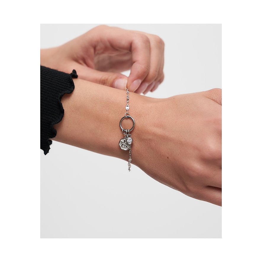 Et Tamaris armbånd i rustfrit stål med et rundt vedhæng og en blomst, båret på et håndled.