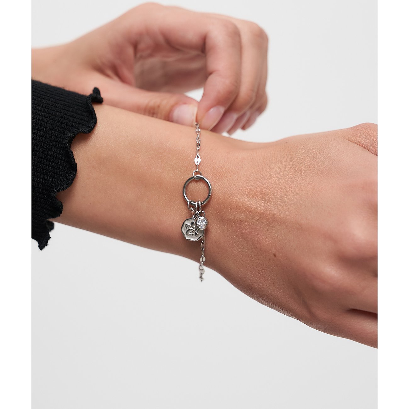 Et Tamaris armbånd i rustfrit stål med et rundt vedhæng og en blomst, båret på et håndled.