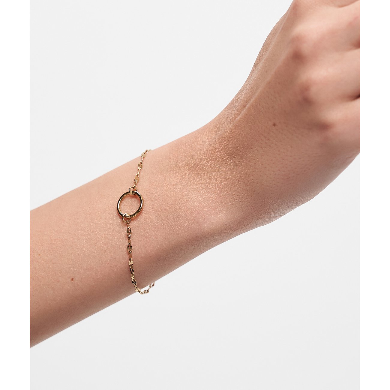 Nærbillede af et guld Tamaris armbånd i rustfrit stål med rundt vedhæng, båret på et håndled.