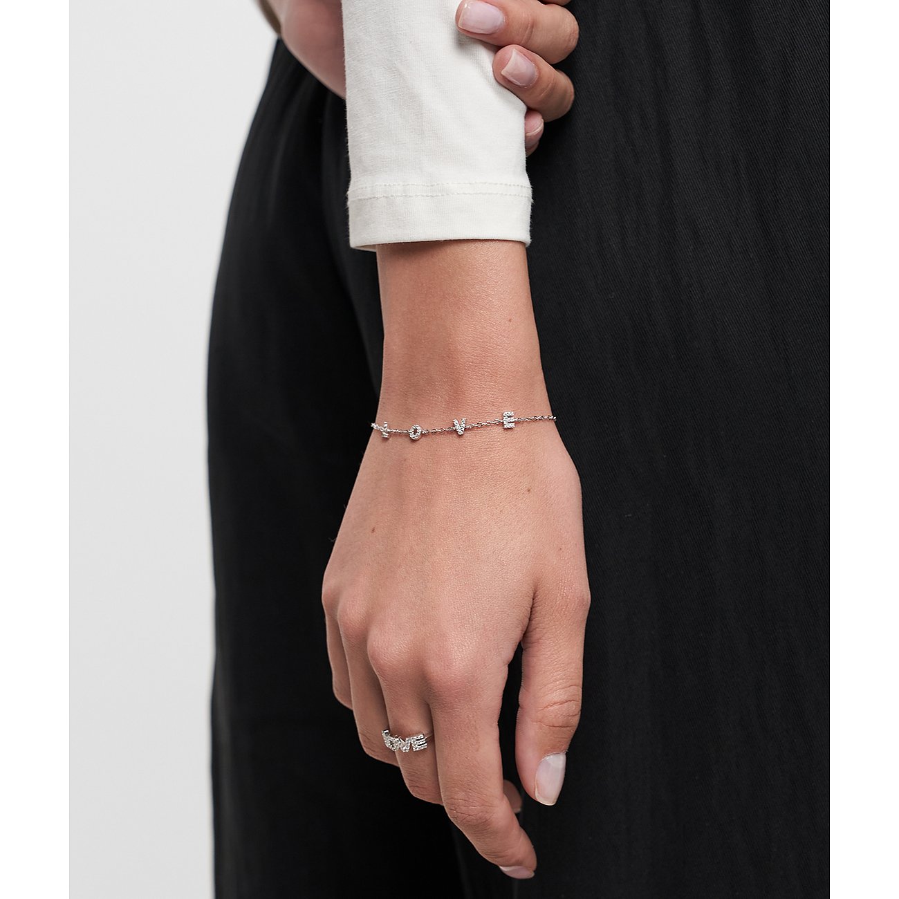 Nahaufnahme eines silberfarbenen Tamaris Armbands mit „LOVE“-Schriftzug und Zirkonia am Handgelenk eines Models.