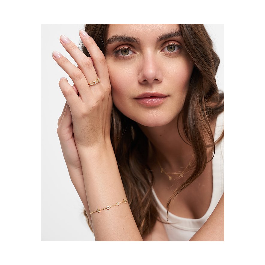 Nahaufnahme einer Frau, die ein goldfarbenes Tamaris Silberarmband mit „LOVE“-Elementen und Zirkonia am Handgelenk trägt.