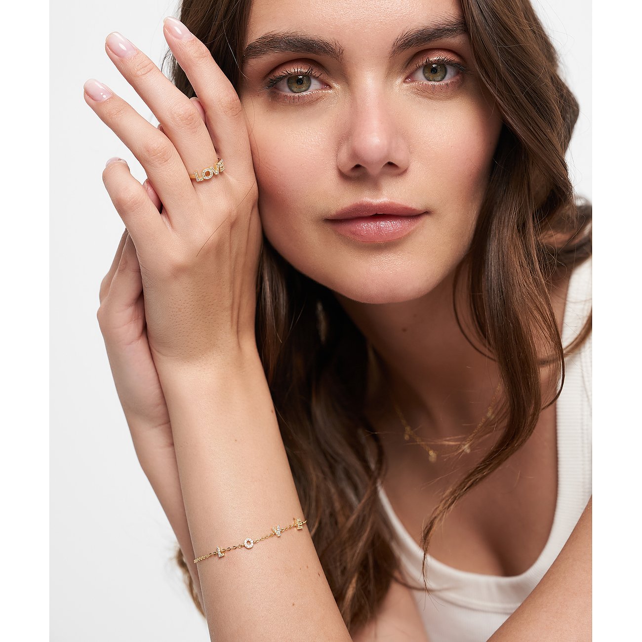 Nahaufnahme einer Frau, die ein goldfarbenes Tamaris Silberarmband mit „LOVE“-Elementen und Zirkonia am Handgelenk trägt.