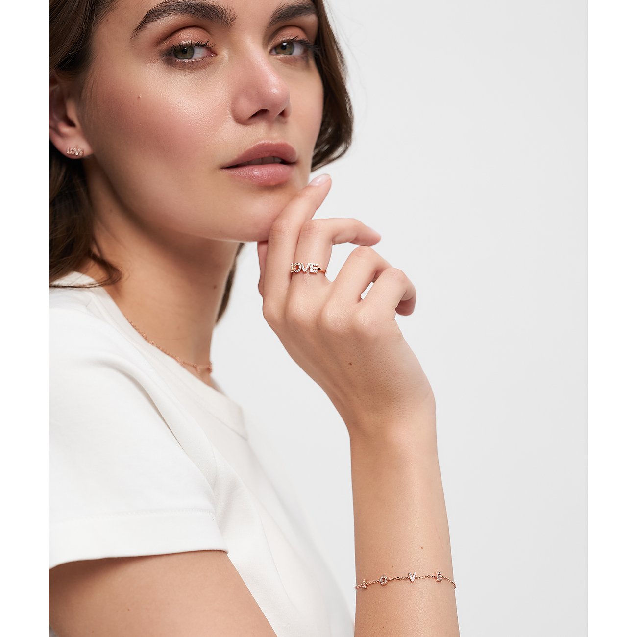 Nahaufnahme eines roségoldenen Silberarmbands mit kleinen „LOVE“-Buchstaben, getragen von einem Model.