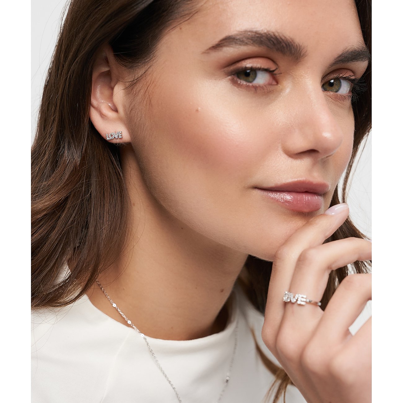 Nahaufnahme einer Frau, die Tamaris Ohrstecker aus 925er Silber mit Zirkonia-Schriftzug „Love“ trägt.